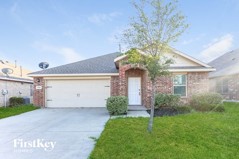 a brick house with a white garage door and a tree