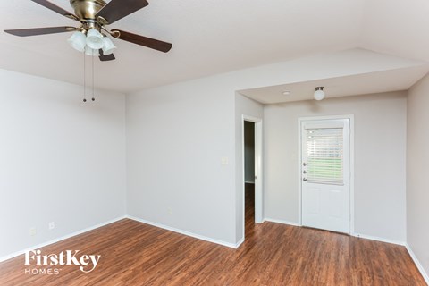 a living room with a ceiling fan and a door to a hallway