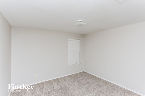 a bedroom with white walls and carpet and a window