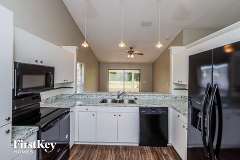 A kitchen with a black dishwasher and a black fridge.
