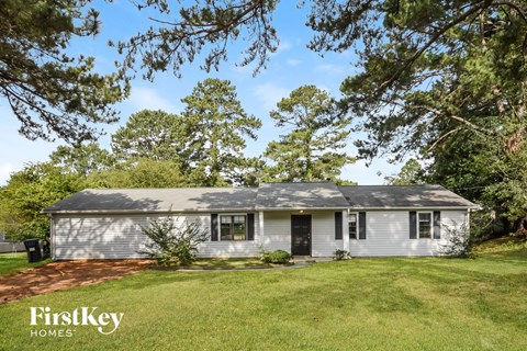 a white house with a grassy yard and trees