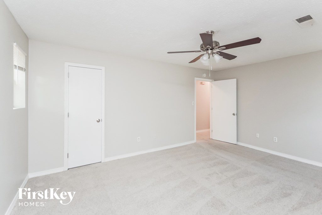 a living room with white carpet and a ceiling fan