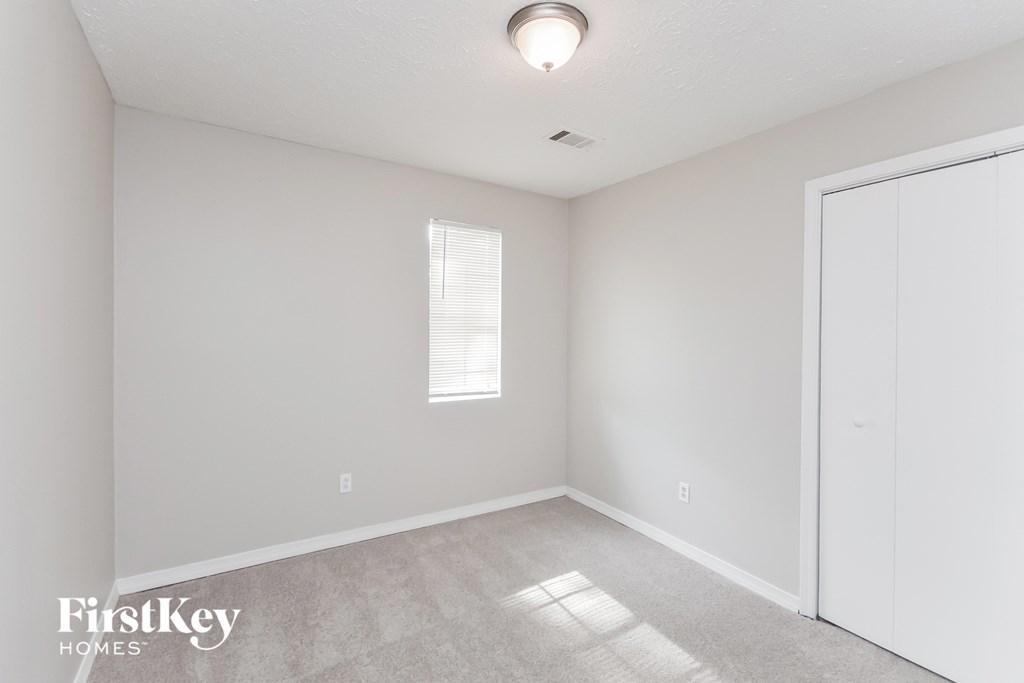 a bedroom with white walls and a door to a closet