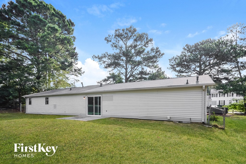 a small white house with a grass yard and trees