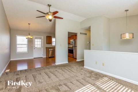A spacious room with a ceiling fan and a rug on the floor.