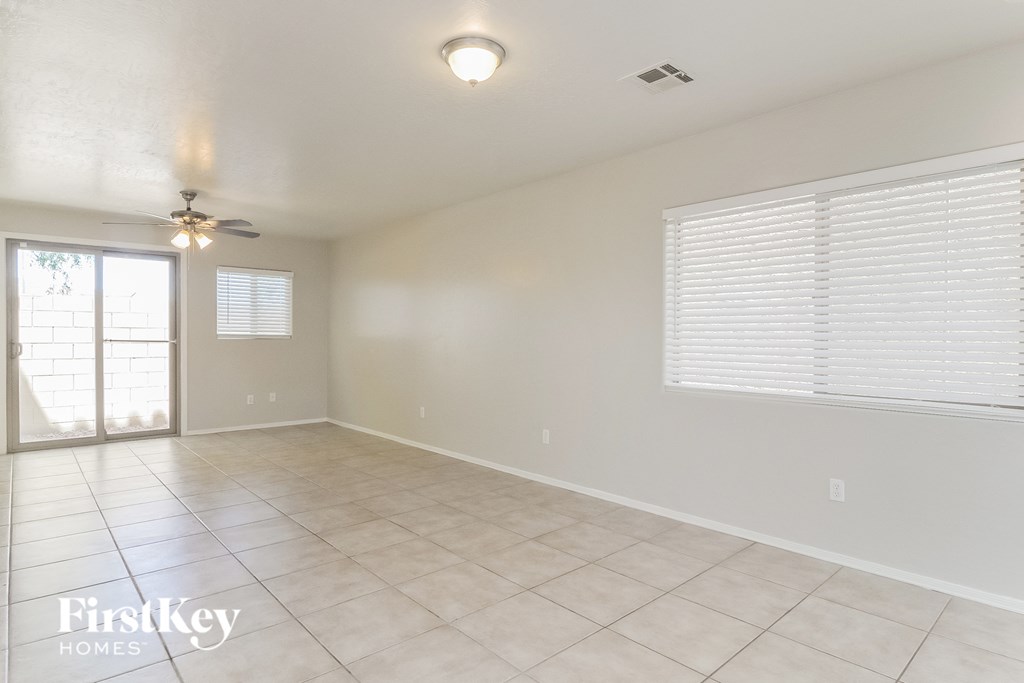 A spacious room with a ceiling fan and sliding glass doors.
