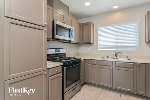 A kitchen with beige cabinets and a FirstKey Homes logo.