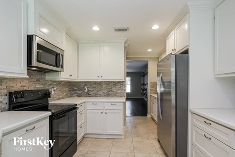 a white kitchen with stainless steel appliances and white cabinets
