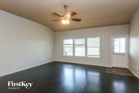 the living room of an empty house with a ceiling fan