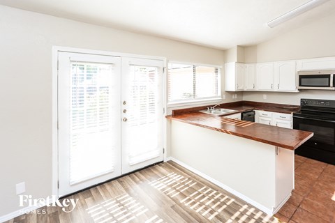 A kitchen with white cabinets and a wooden countertop.