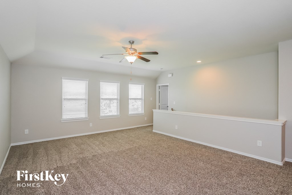 a spacious living room with carpet and a ceiling fan