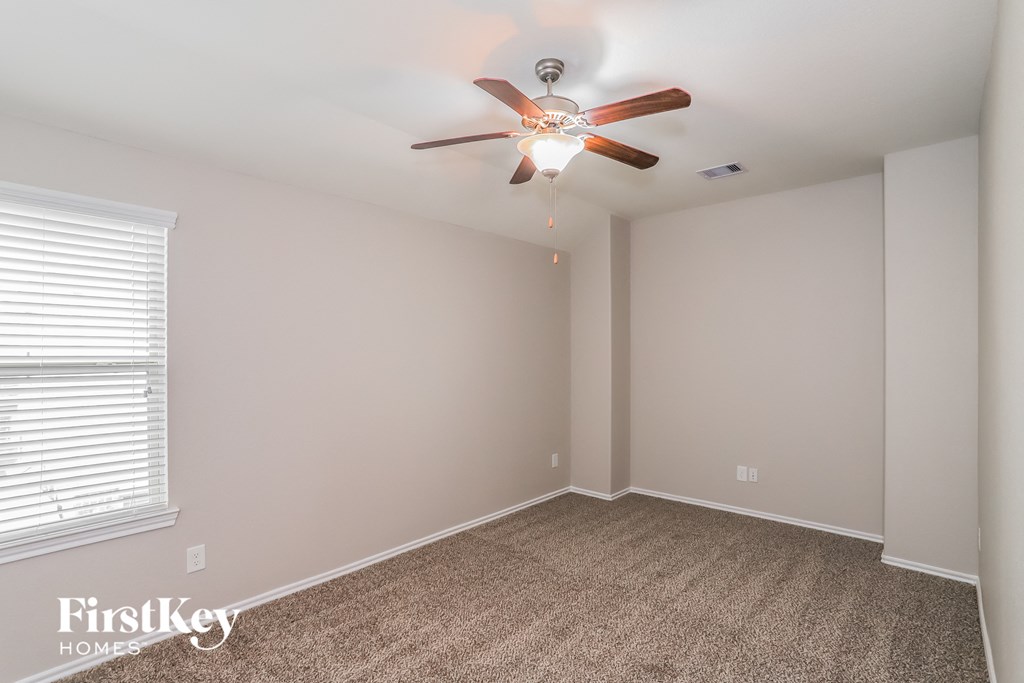 the upstairs bedroom has a ceiling fan and a large window