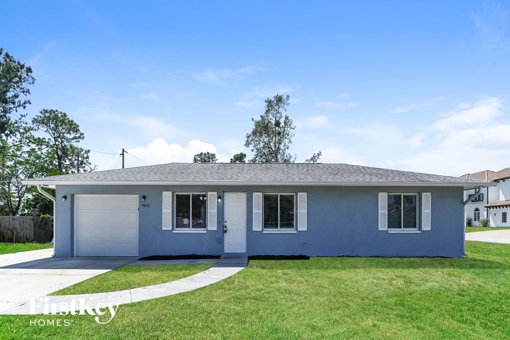 A blue house with a white garage door and a driveway.