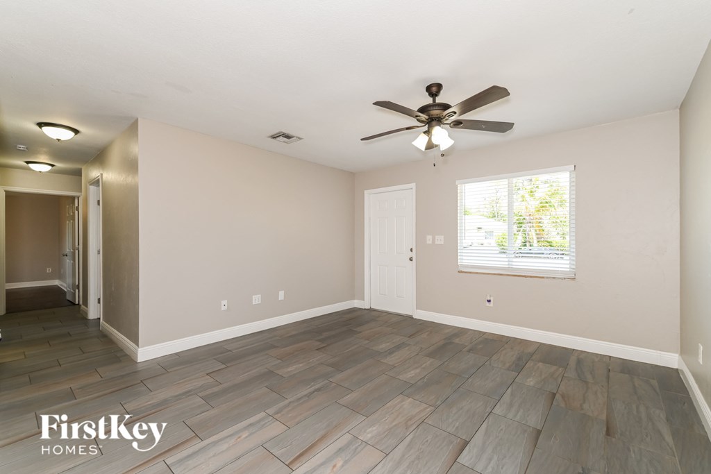 A room with a ceiling fan and wooden flooring.