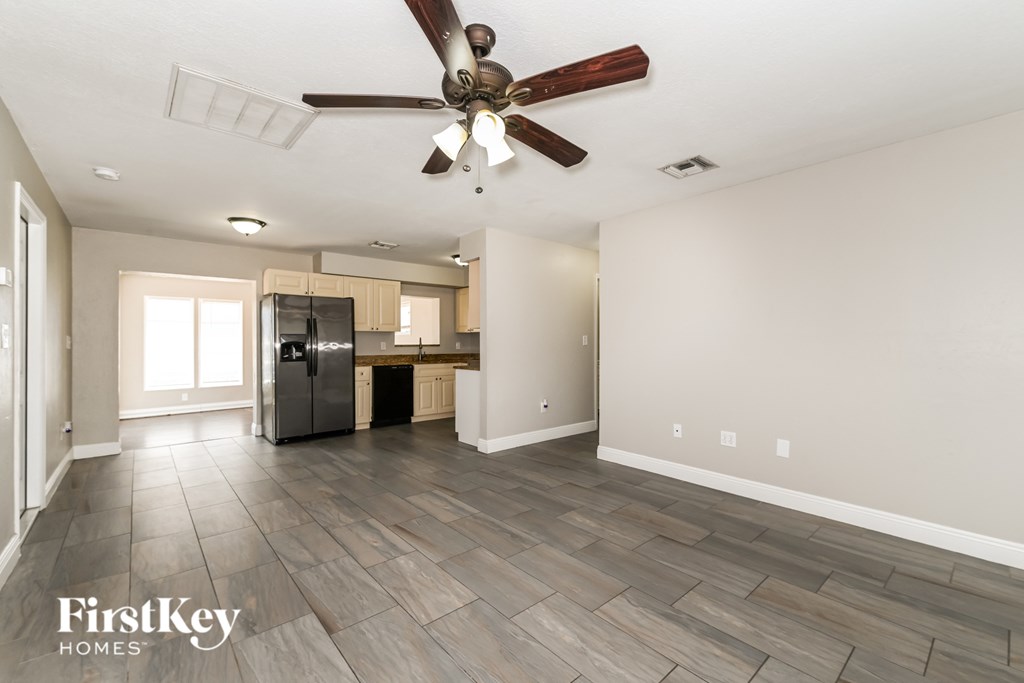 A spacious room with a ceiling fan and wooden flooring.