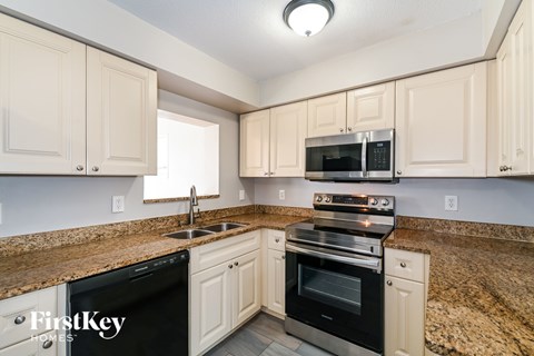 A kitchen with a black dishwasher and a black microwave above the stove.
