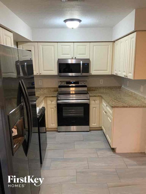 A kitchen with a refrigerator, microwave, oven, and cabinets.
