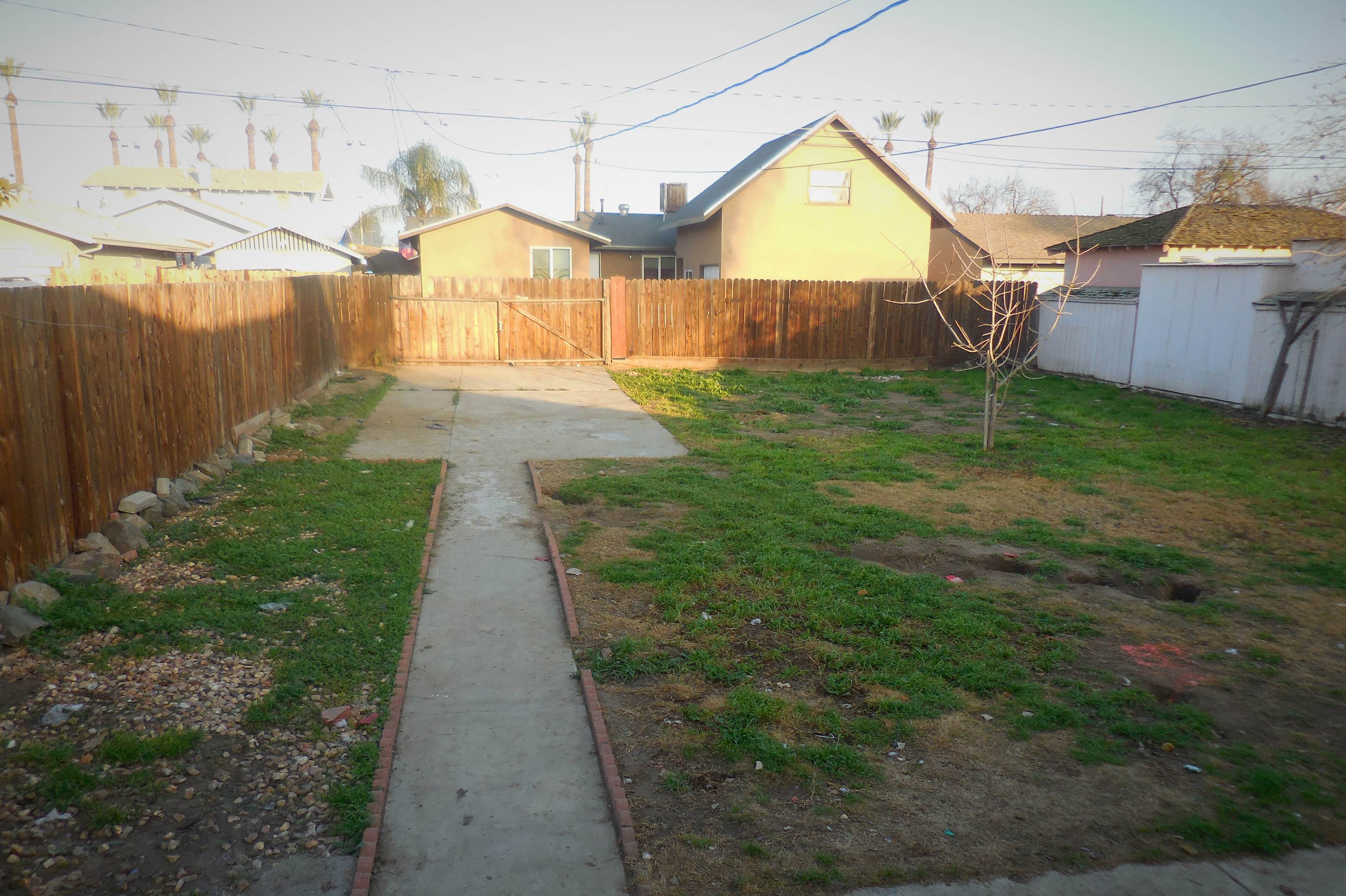 the backyard of a house with a fence and a sidewalk