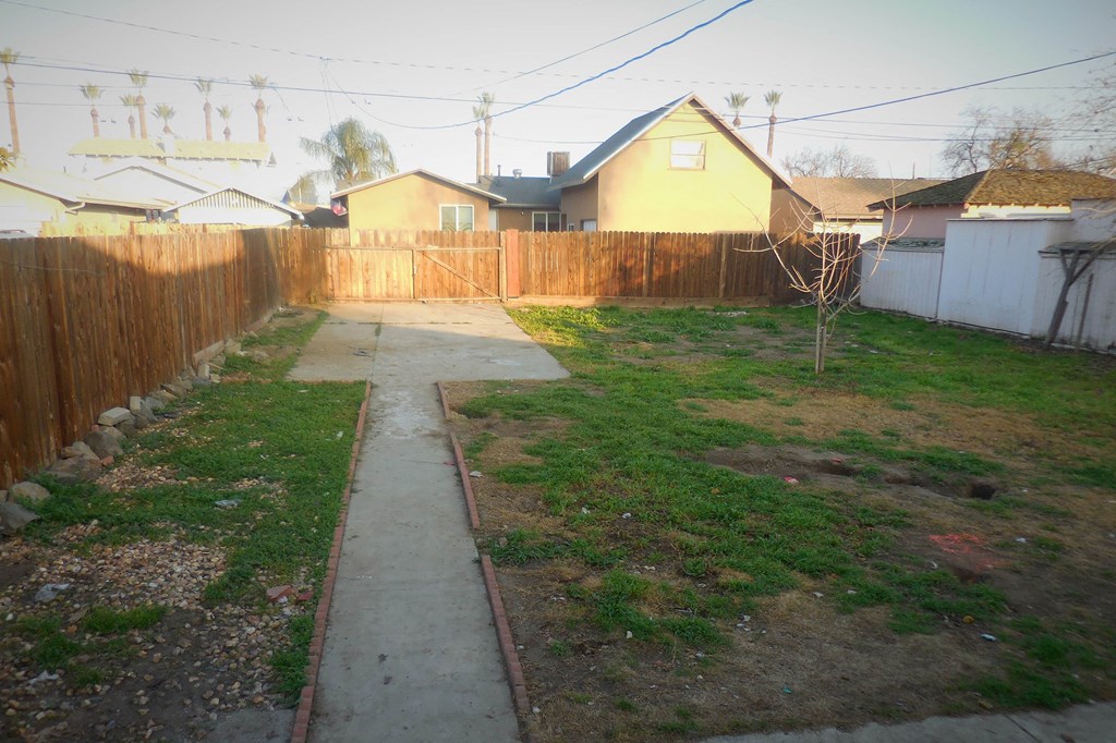 the backyard of a house with a fence and a sidewalk