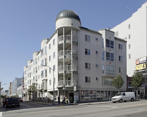 A white building with a green dome on top is situated on a street corner.