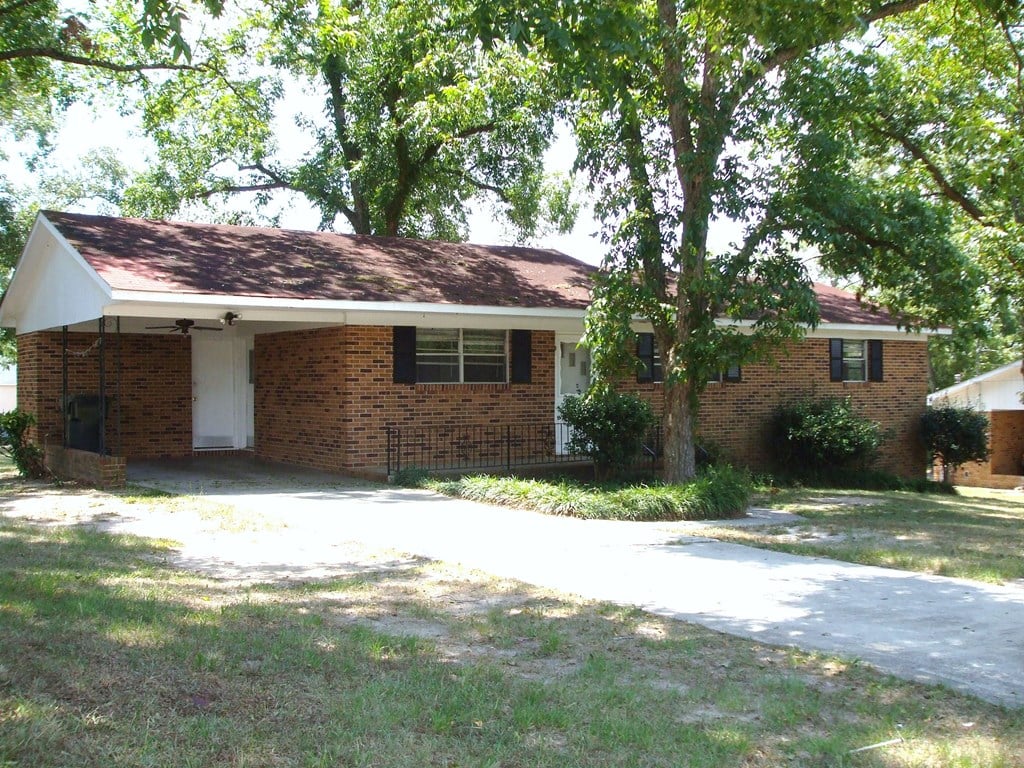 a brick house with a sidewalk and some trees