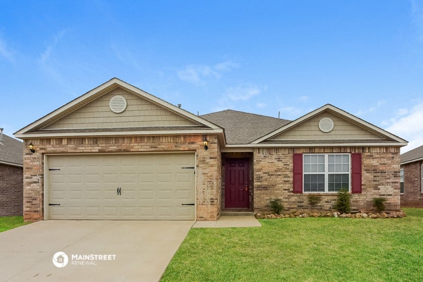 a home with a tan garage door and a brick house