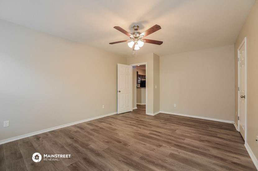 the spacious living room with ceiling fan and wood flooring