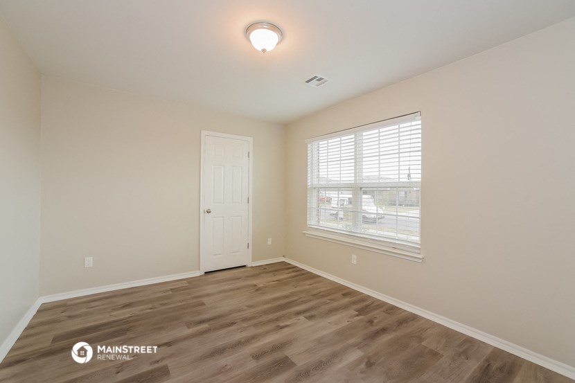 the spacious living room with a large window and wood flooring