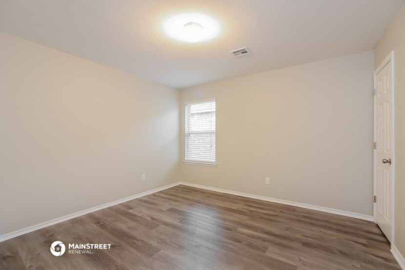 the spacious living room with wood flooring and white walls
