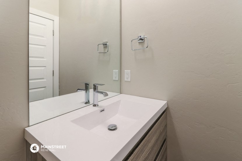 the bathroom has a large mirror and a white sink