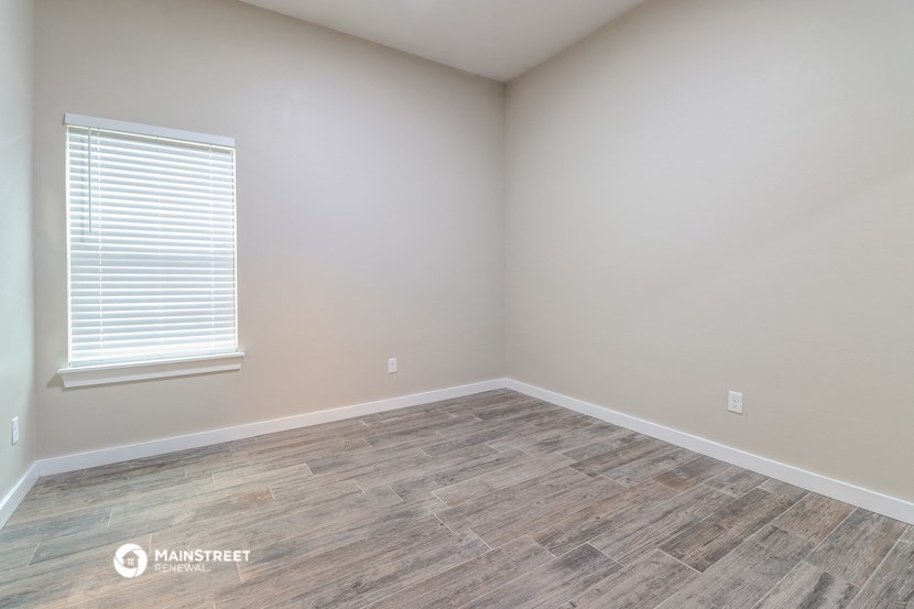 an empty room with wood flooring and a window