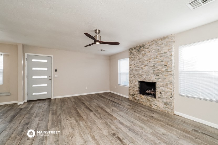 an empty living room with a fireplace and a ceiling fan