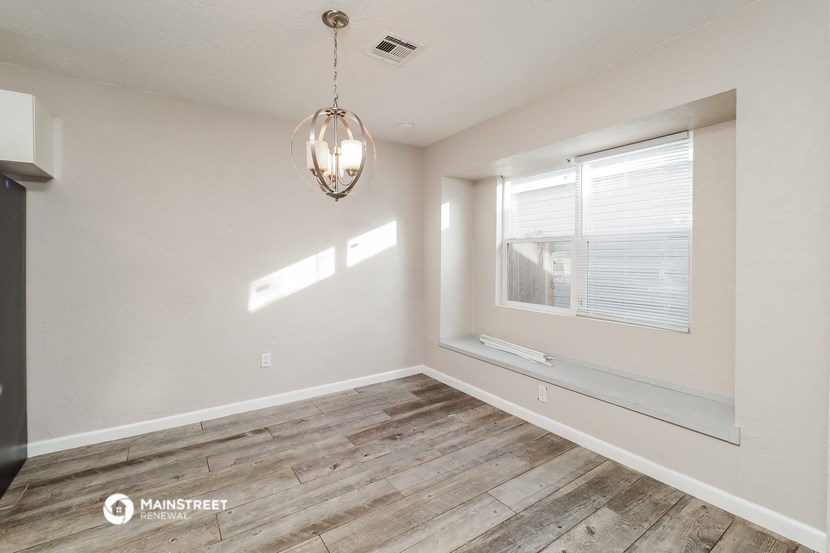 an empty living room with a large window and wood flooring