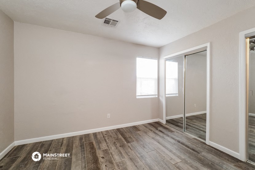 an empty room with a ceiling fan and a mirrored closet