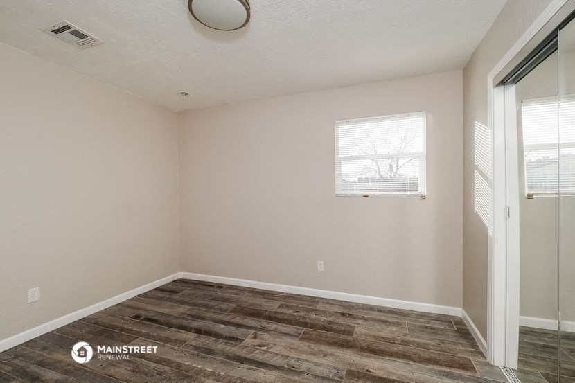 the living room of a home with wood flooring and a window
