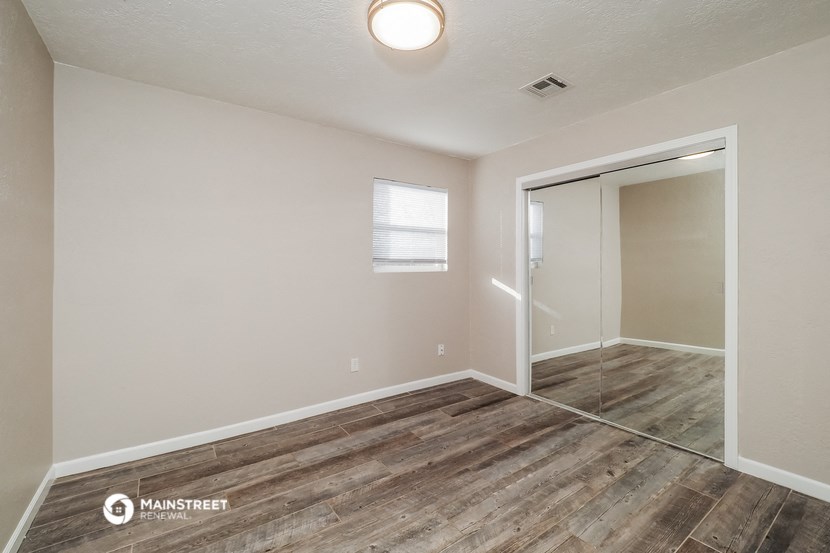 an empty living room with a door to a closet and a window