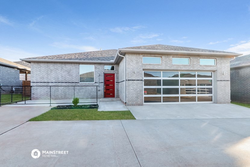 a white brick house with a red door and a driveway