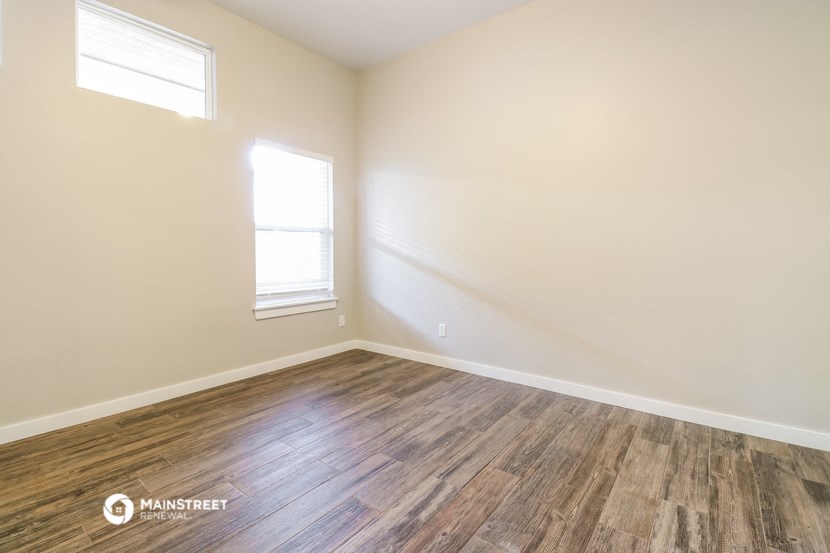 the interior of an empty room with wood flooring and a window