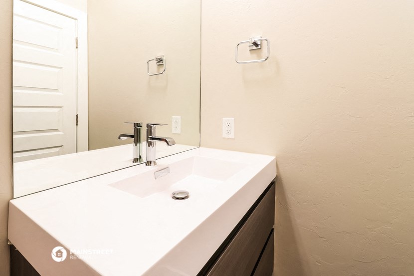 the bathroom has a large mirror and a white sink
