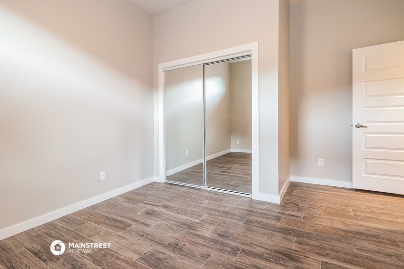 a bedroom with a mirrored closet and wood flooring