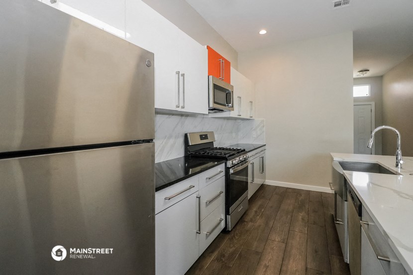 renovated kitchen with stainless steel appliances and white cabinets in an apartment