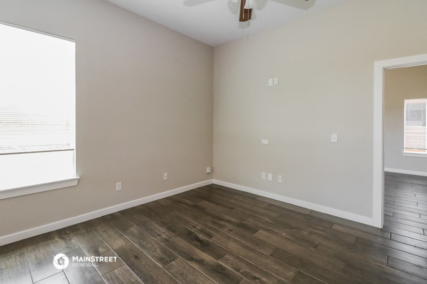 the interior of an empty room with wood flooring and a window