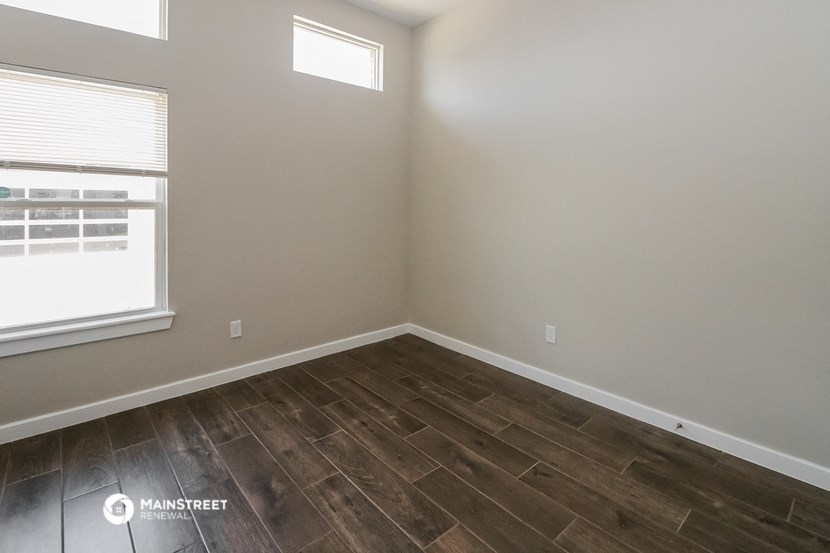 the interior of a bedroom with wooden flooring and a window