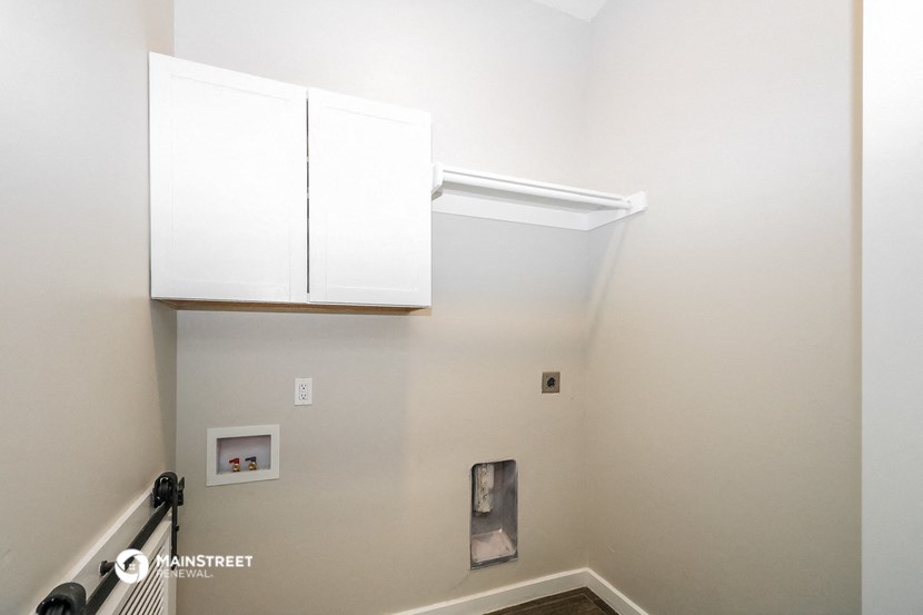 a stairwell with two white cabinets on the wall and a railing with a staircase