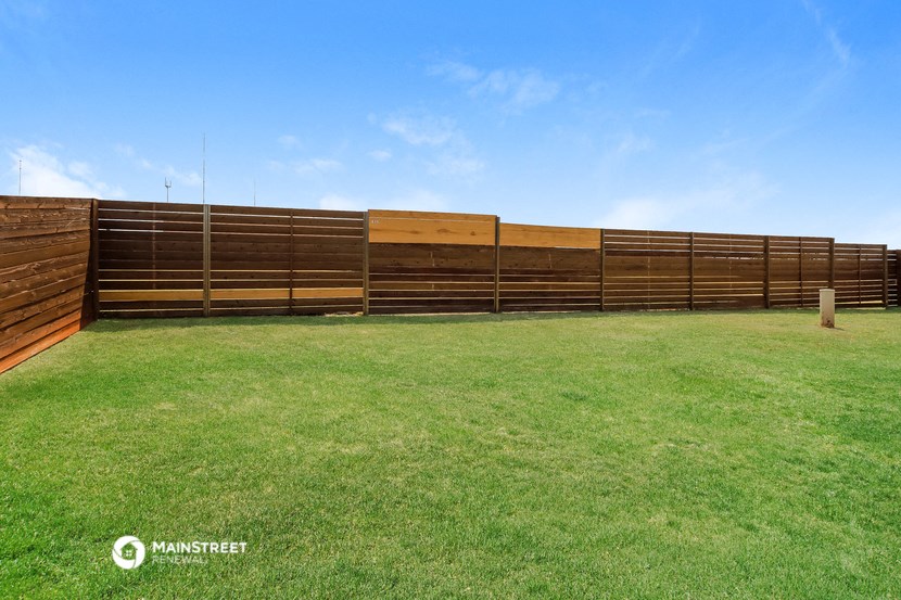 a wooden fence in front of a grass field