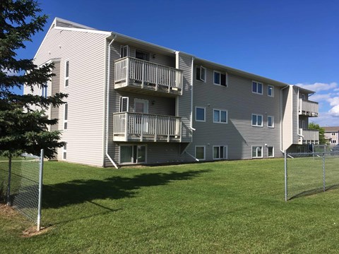 the back of an apartment building with balconies and a lawn