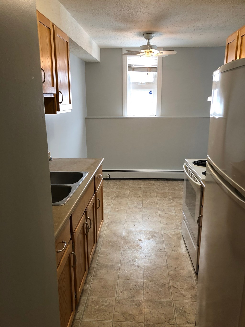 an empty kitchen with a sink and a refrigerator