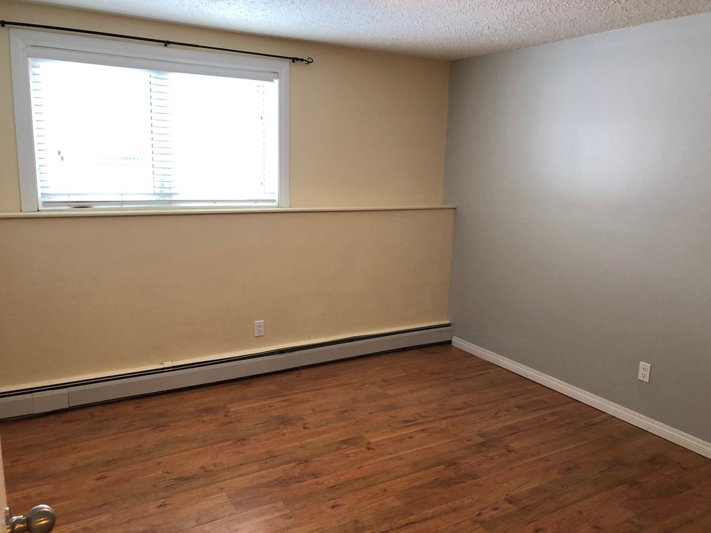 a bedroom with wood flooring and a window