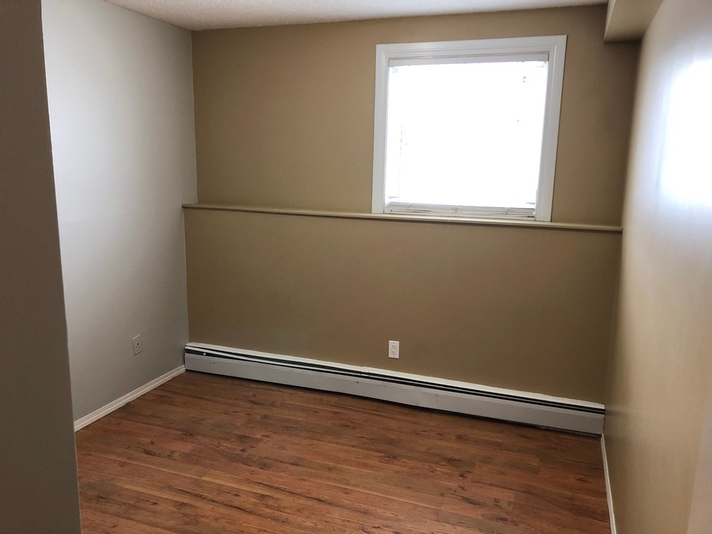 an empty room with a window and wooden floors