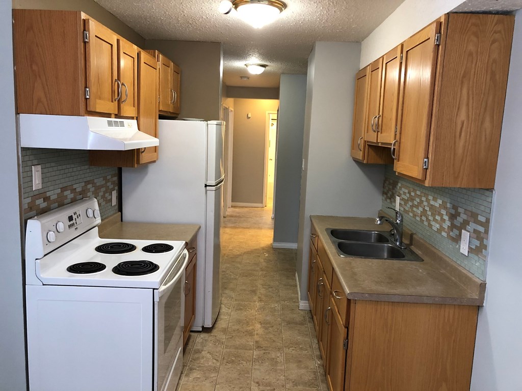 an empty kitchen with a stove refrigerator and sink